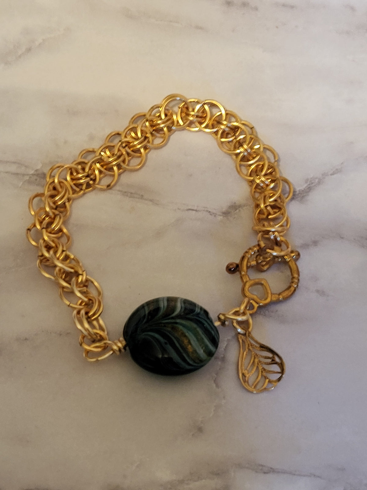 Gold tone chain mail bracelet with green bead
